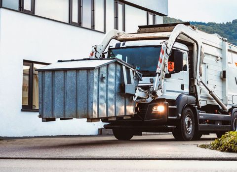Frontlader von Weber hebt Umleerbehälter hoch.
